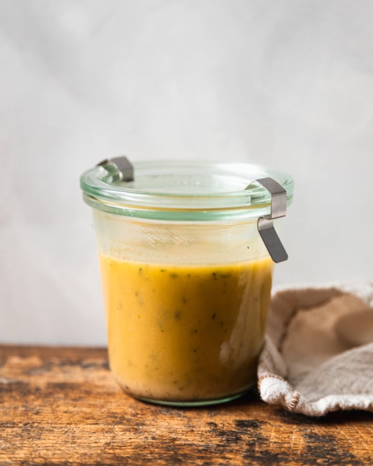 A head-on shot of a jar of red wine vinegar and thyme dressing.