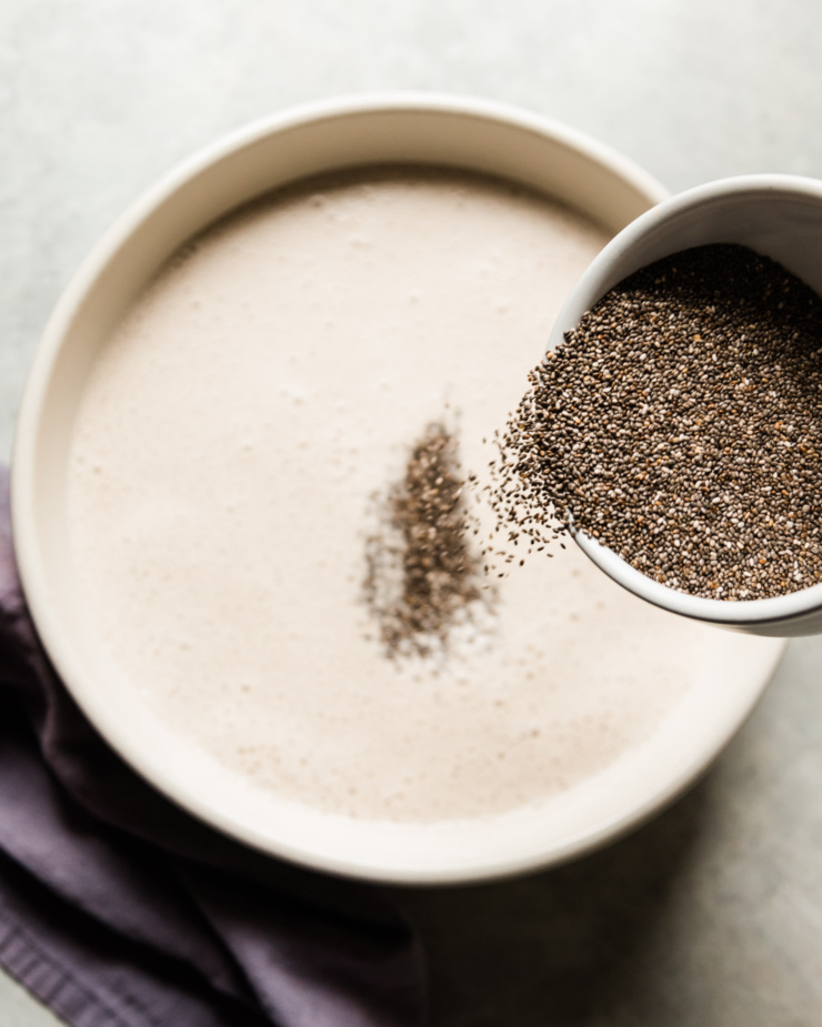 An overhead shot shows chia seeds being poured into a bowl of earl grey-infused cashew milk.