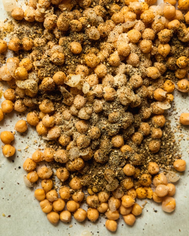 An overhead shot shows chickpeas that are heavily seasoned with za'atar, garlic powder, salt, and pepper--before being roasted in the oven.
