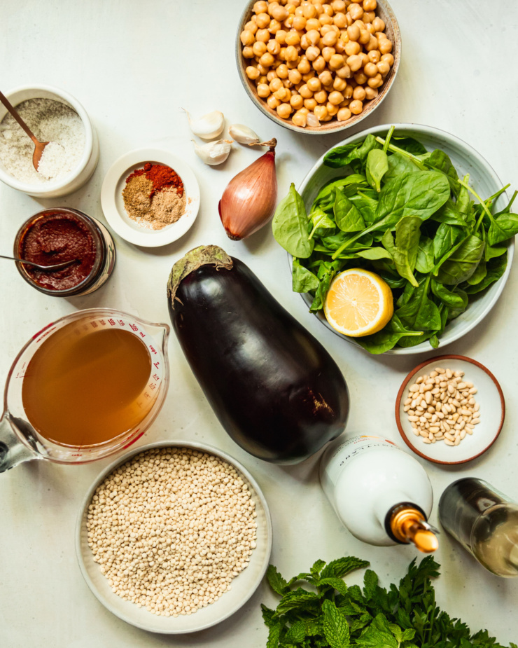 An overhead shot shows ingredients used in a one-pan harissa eggplant and pearl couscous dish.