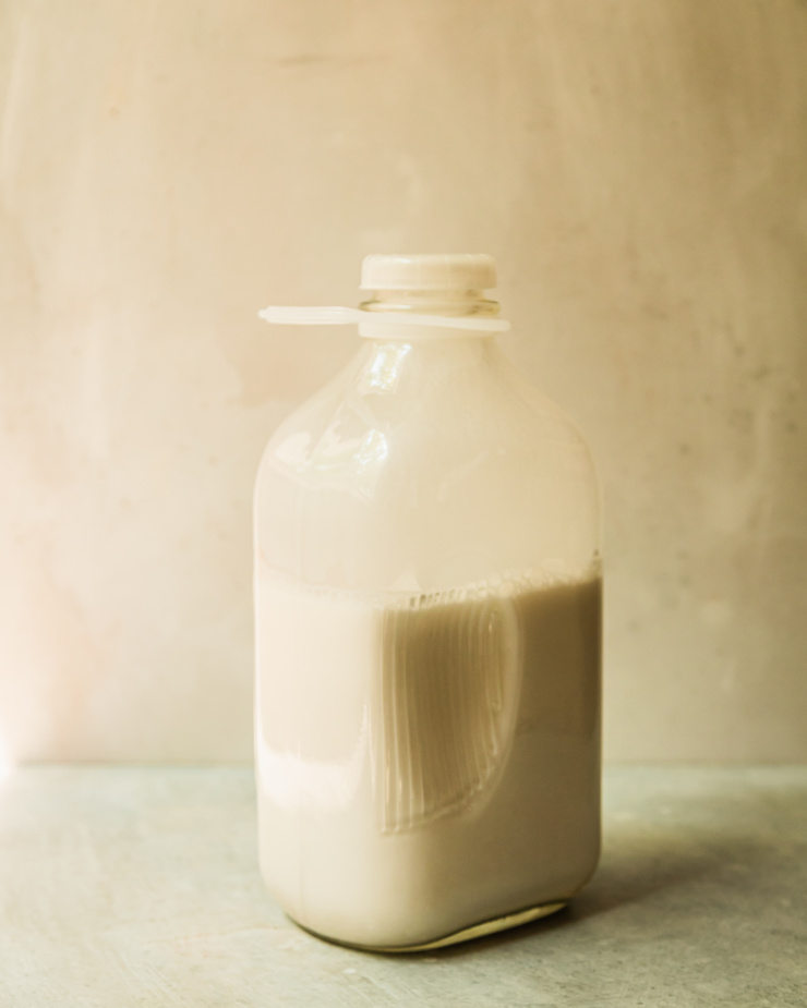 A head-on shot shows a glass jug that is 2/3 full with homemade nut milk.