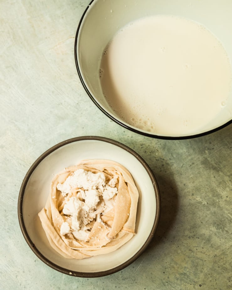 An overhead shot shows freshly made nut milk and another bowl with the nut pulp in a nut milk bag.