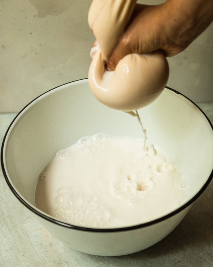 A 3/4 angle shows a nut milk bag being squeezed over a bowl of strained nut milk.