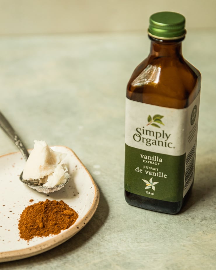 A 3/4 angle image shows a bottle of vanilla extract and a small plate with some ground cinnamon and a spoonful of coconut butter.