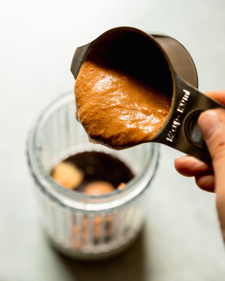 An overhead image shows peanut butter being poured into a blender cup.