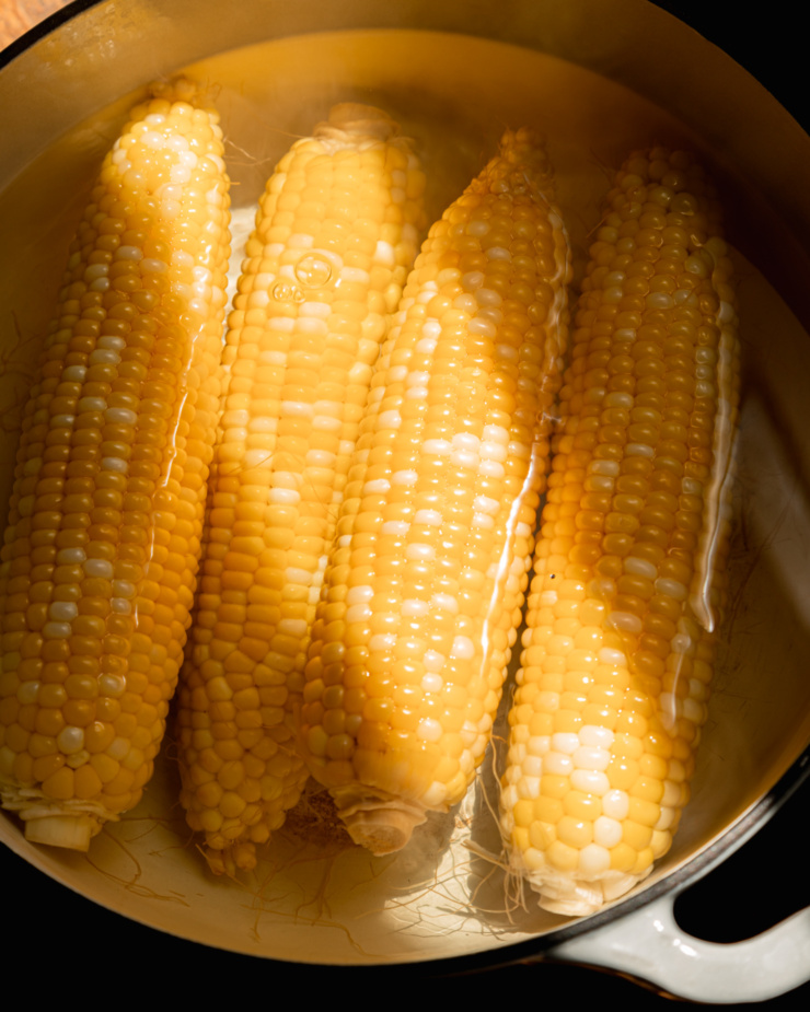 An up close shot of corn cobs floating in a pot of water.
