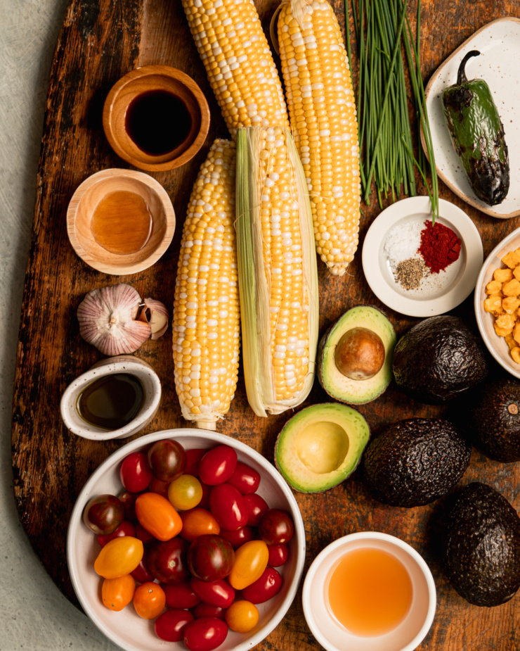 An overhead shot of ingredients for a summery salad, all on top of a worn wooden cutting board.
