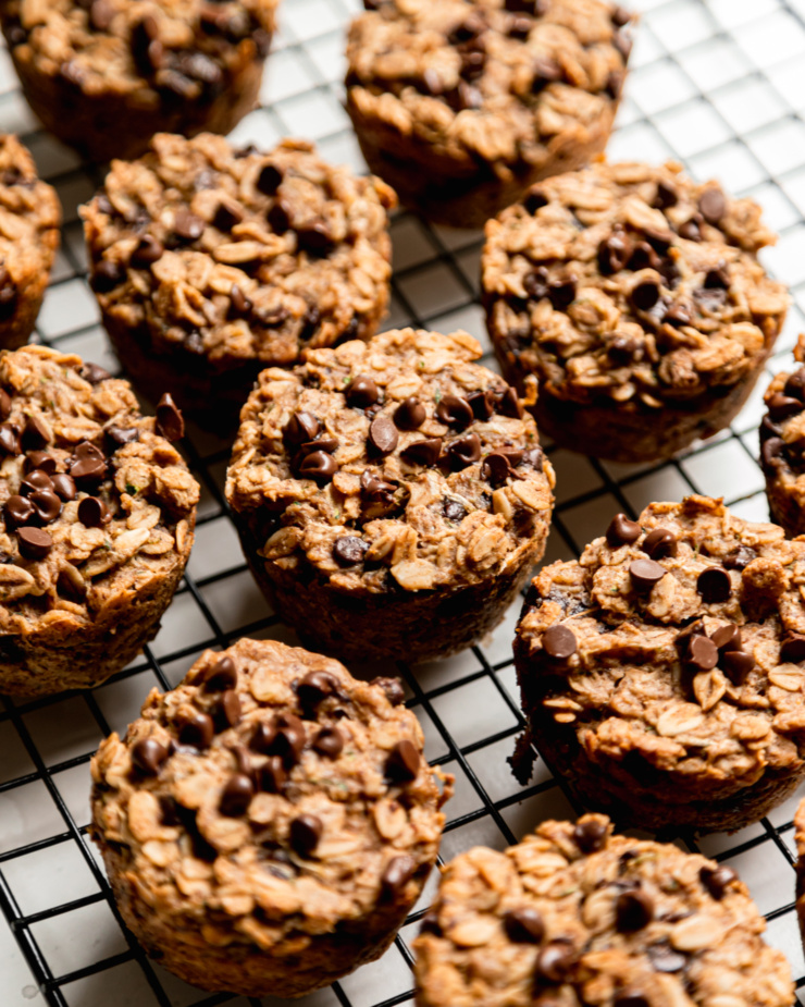 A 3/4 angle shot shows a bunch of baked zucchini oatmeal cups cooling on a wore rack.