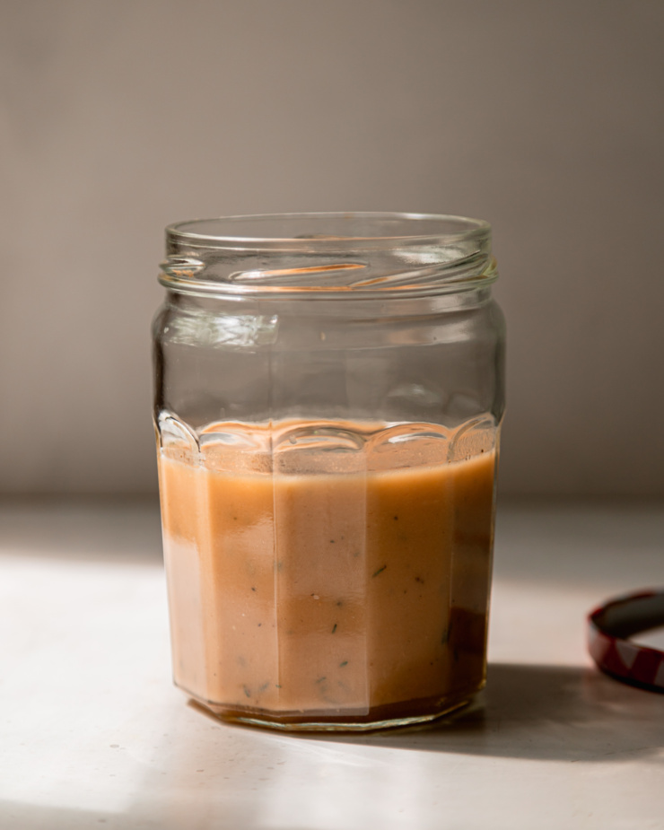 A head-on shot of a jar of red wine vinegar dressing with thyme.
