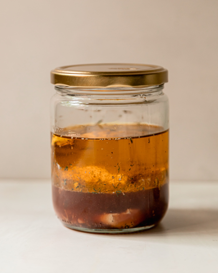 A head-on shot shows a red wine vinegar salad dressing in a sealed jar, prior to shaking up to combine.