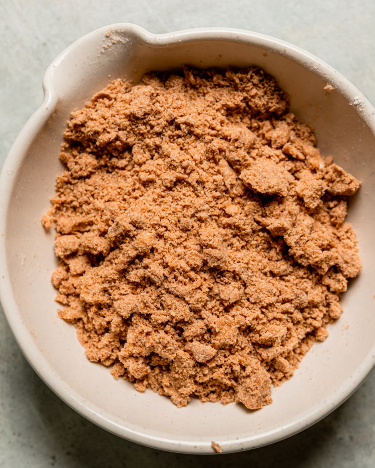 An overhead shot shows a batch of vegan streusel in a ceramic bowl.