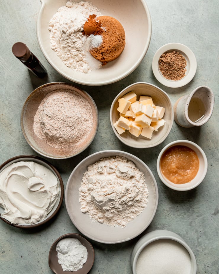 An overhead shot shows measured out ingredients for a batch of muffins. Most ingredients are in small ceramic bowls.