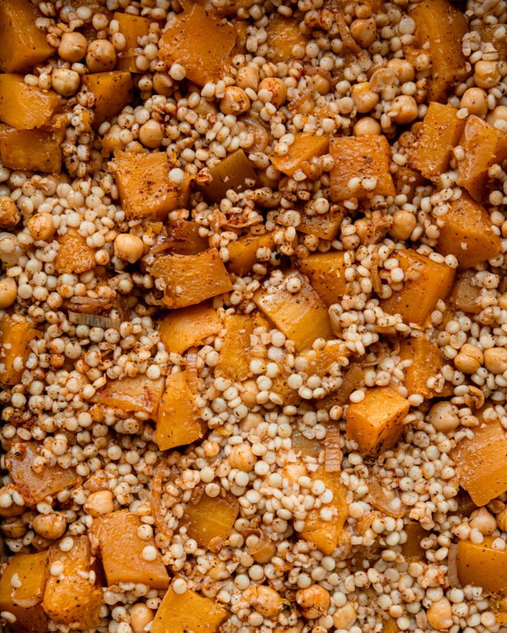 An up close, overhead shot shows baked pearl couscous and butternut squash cubes.