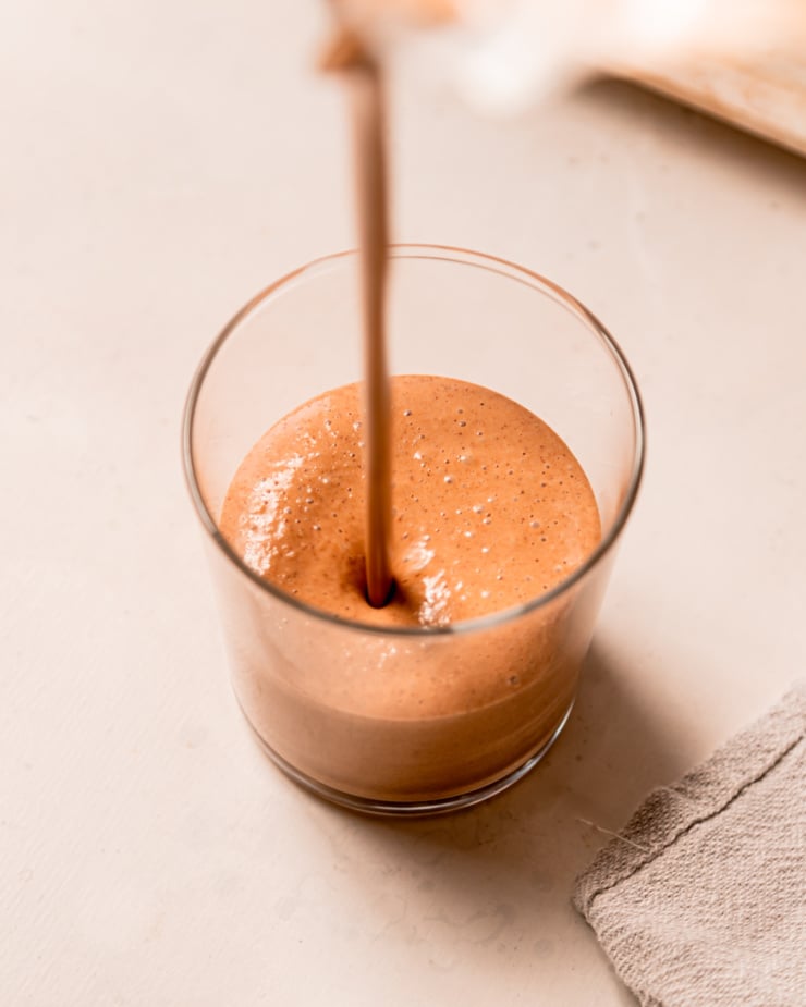 A slight overhead shot shows a smoothie being poured into a glass