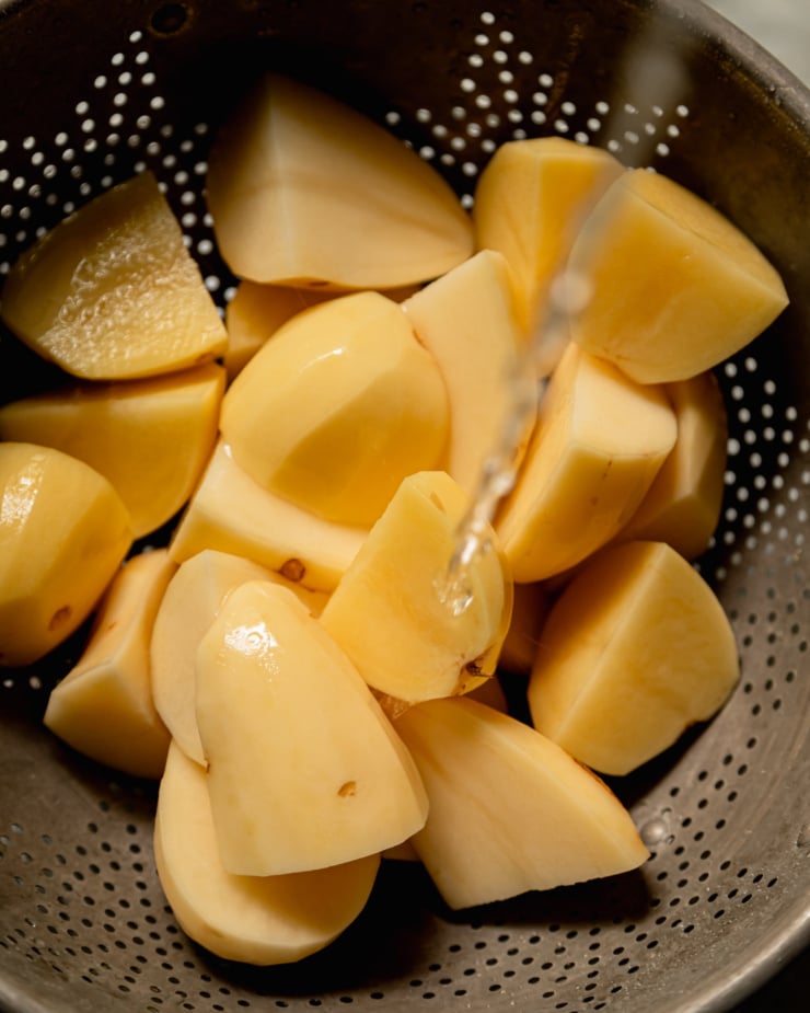 An overhead shot shows peeled, diced potatoes being rinsed with cold water.