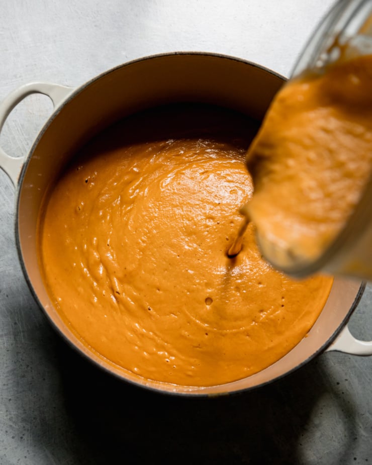 An overhead shot shows blended vegan butternut squash being poured from a blender to a pot.