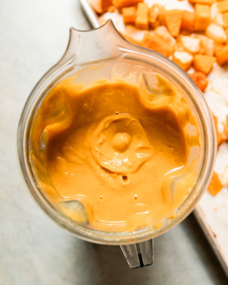 An overhead shot shows blended vegan butternut squash soup in a blender pitcher.