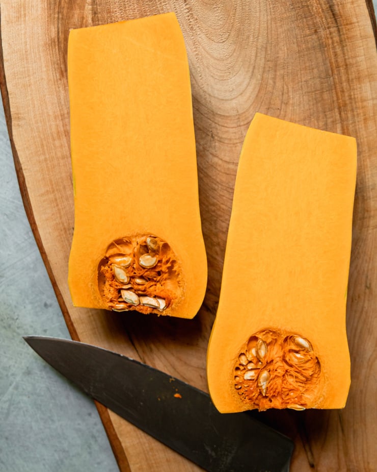 An overhead shot shows a peeled butternut squash that has been cut in half lengthwise.