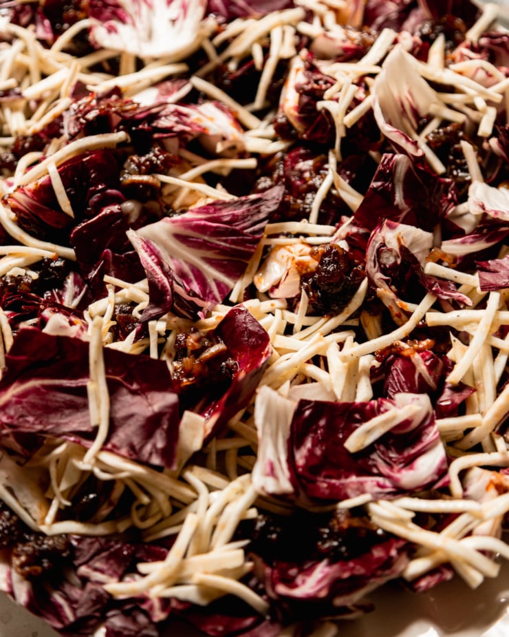 An up close shot shows chopped radicchio and julienned celery root with bits of warm date dressing.