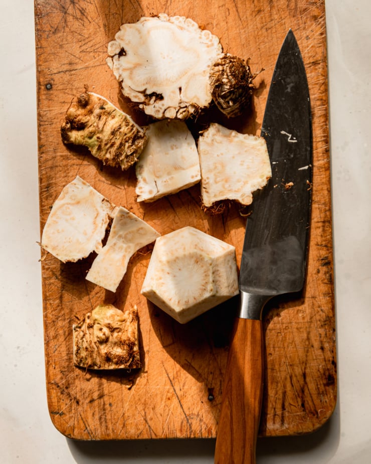 An overhead shot shows a knife on a cutting board with a peeled celery root.