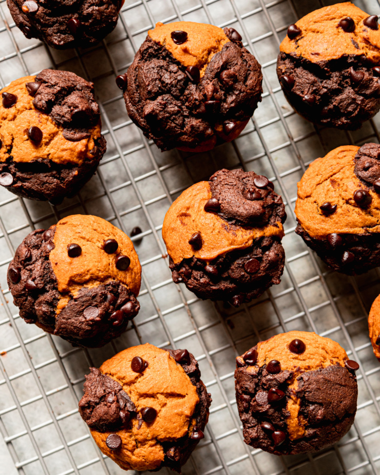 An overhead shot shows. batch of pumpkin chocolate muffins with a marbled appearance on a cooling rack.