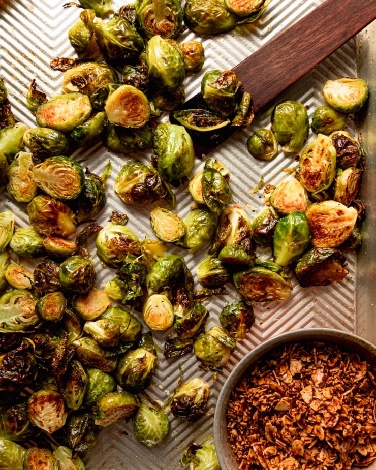 An overhead shot shows a baking sheet with cooked Brussels sprouts and a small bowl of smoky maple almond "bits"