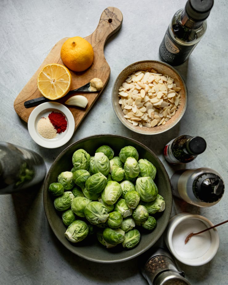 An overhead shot shows ingredients used in a Brussels sprout side dish that is finished with toasted smoky and maple almond bits.