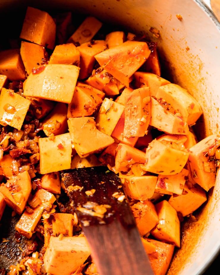 An overhead shot shows diced squash in a pot with sautรฉed onions and spices.