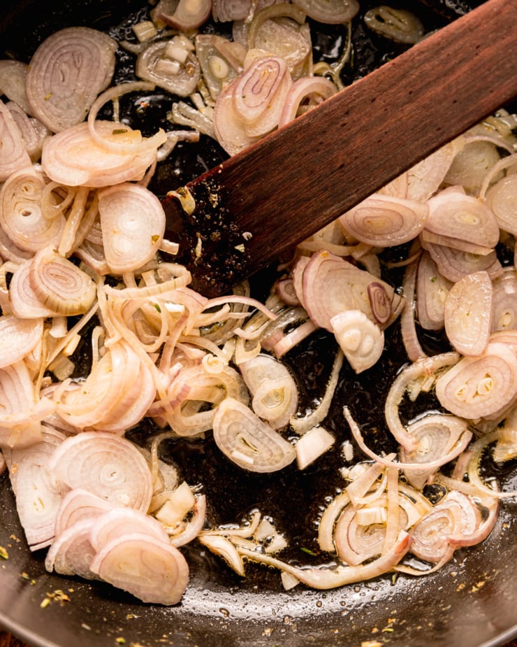 An up close, overhead shot shows shallots sautéing in sizzling olive oil.