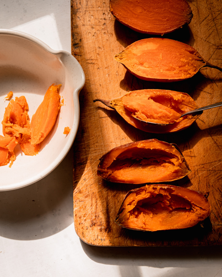 An overhead shot shows baked sweet potato halves being scooped out with a spoon.