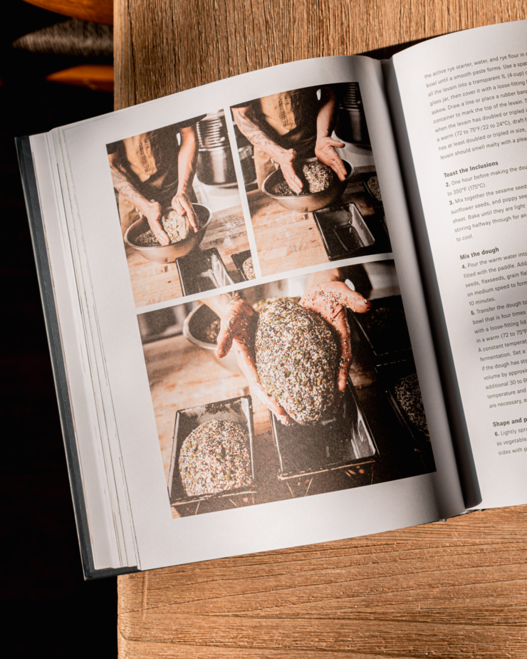 An overhead shot shows a photo spread of a seeded bread being made in a cookbook.