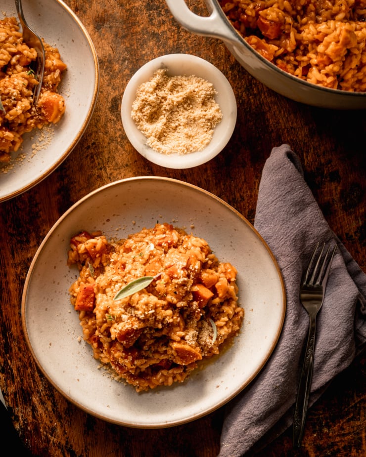 An overhead shot shows two servings of vegan butternut squash next to a pot of the risotto.