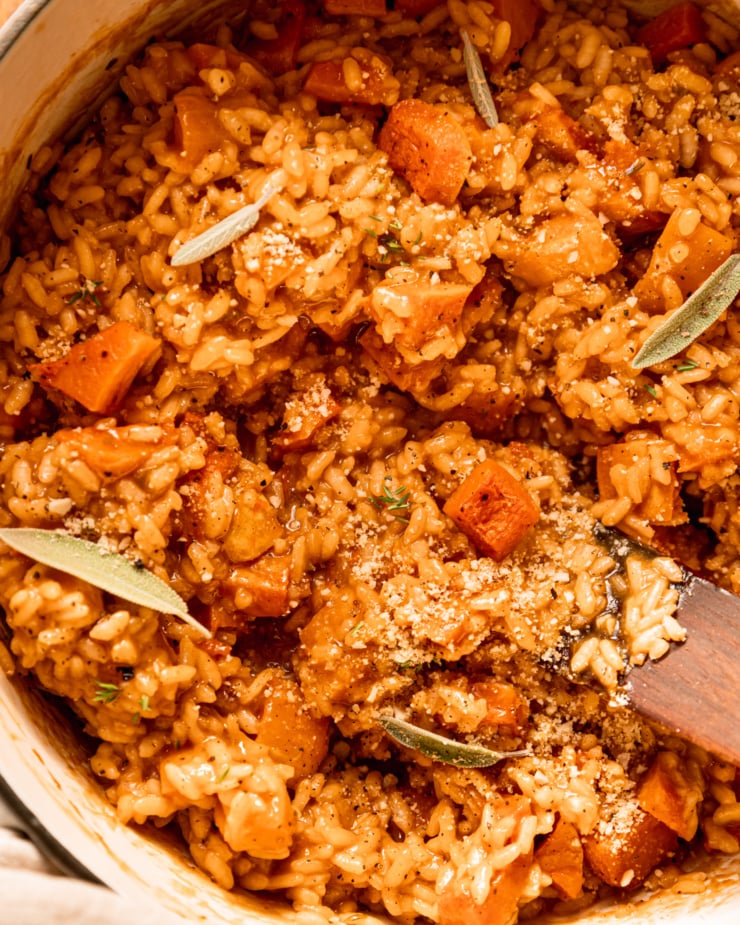 An up close, overhead shot shows a creamy risotto in a pot with chunks of butternut squash.