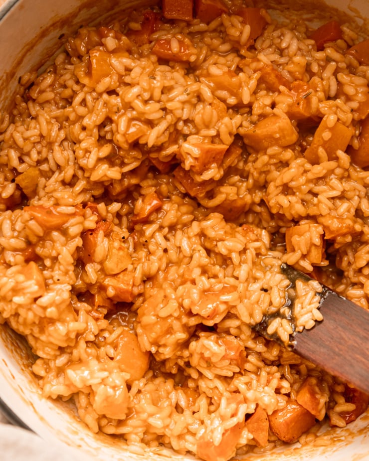 An up close, overhead shot shows a creamy vegan butternut squash risotto in a pot.