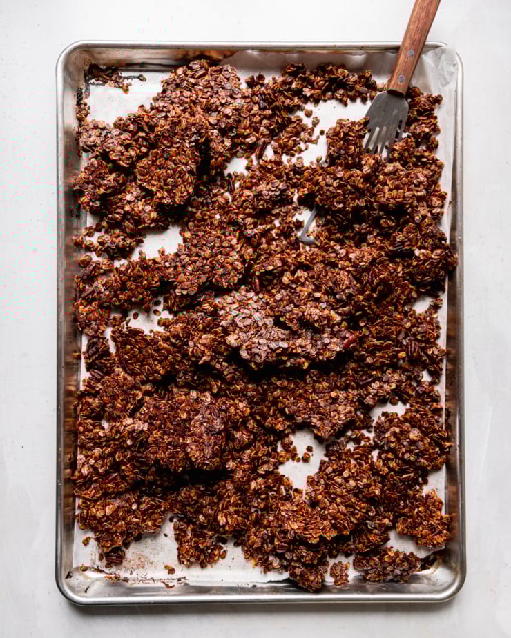 An overhead shot shows a baking sheet filled with deep brown ginger molasses granola.