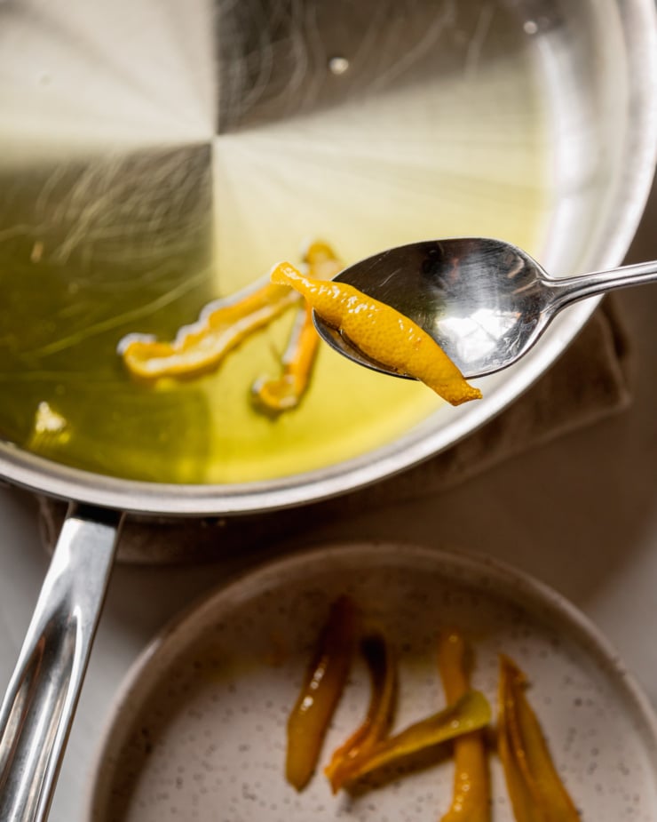 An overhead shot shows lemon peels being spooned out of hot oil onto a plate.