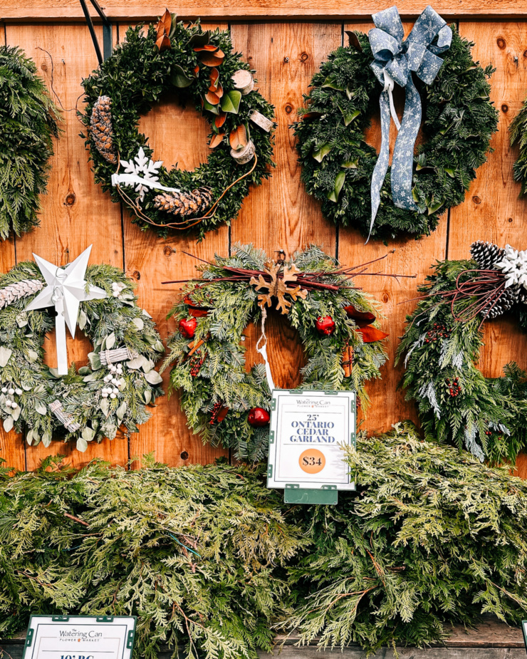 A head-on shot shows a display of natural wreaths made of evergreens with bows and other ornaments.