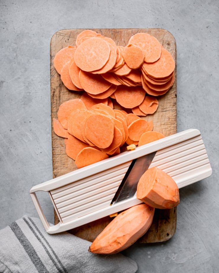 An overhead shot shows thinly sliced sweet potatoes on a cutting board with a mandoline slicer.