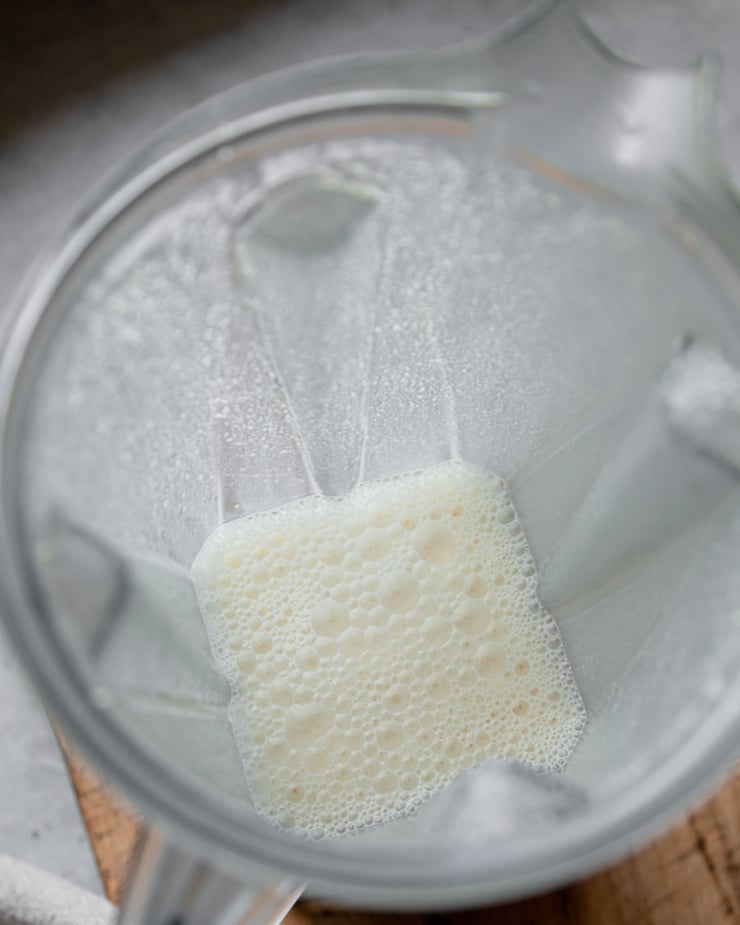 An overhead shot shows some cashew "cream" in a blender pitcher.