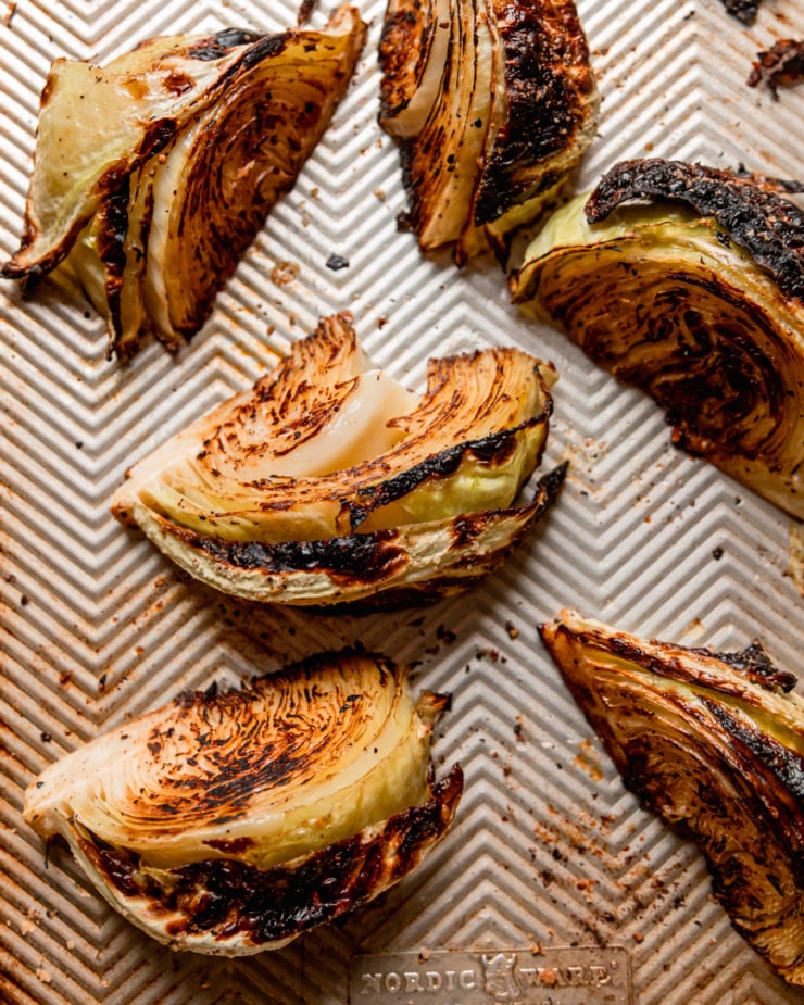 An overhead shot shows well-browned roasted cabbage wedges on a fluted baking sheet.