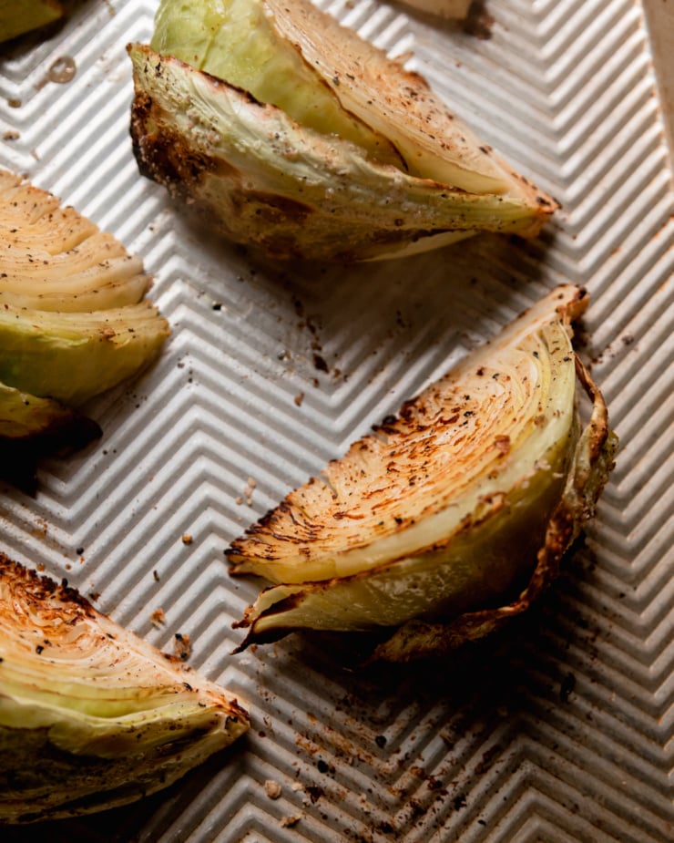 An overhead shot shows roasted wedges of cabbage on a baking sheet.
