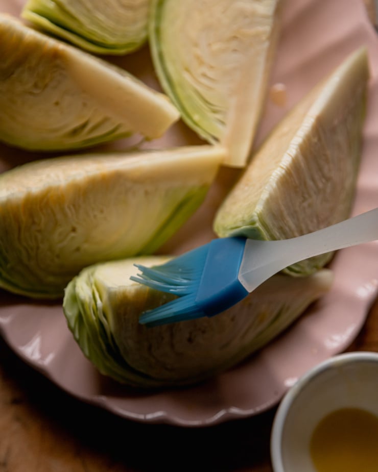 An overhead shot shows cabbage pieces being brushed with oil.