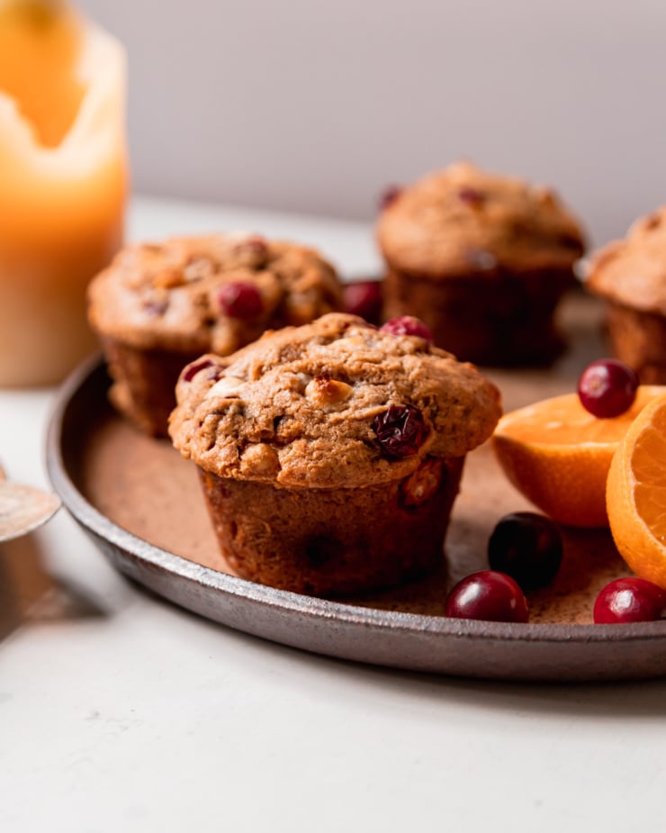 An up close, head-on shot shows a vegan cranberry clementine muffin on a plate.