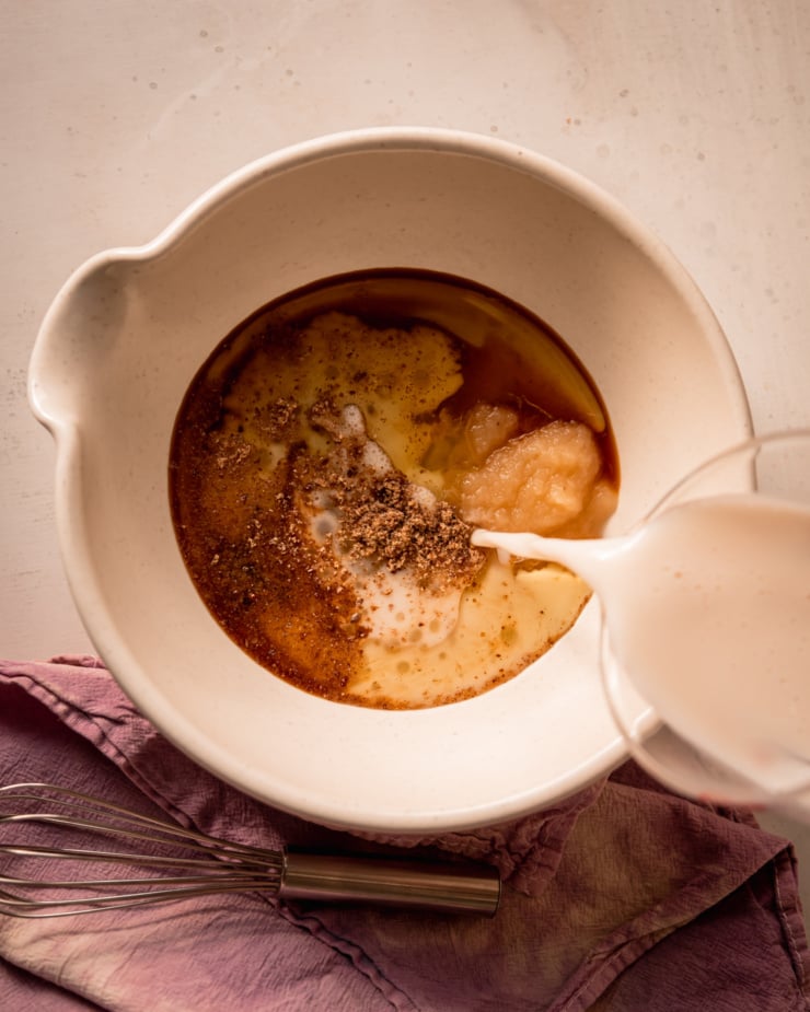 An overhead shot shows almond milk being poured into a bowl with other liquid ingredients and ground flax.