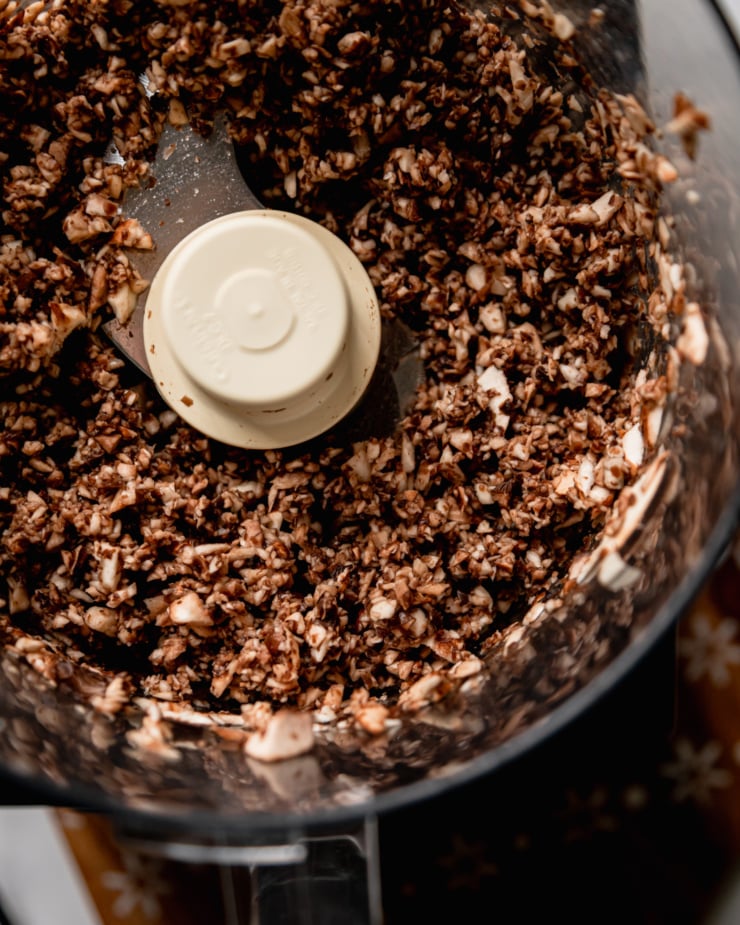An overhead shot shows very finely chopped mushrooms in the bowl of a food processor.