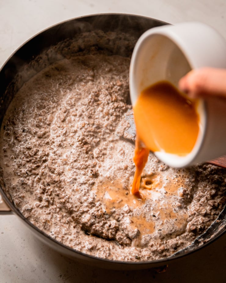 A slight 3/4 angle shot shows a concentrated water and miso mixture being added to a creamy mushroom sauce.
