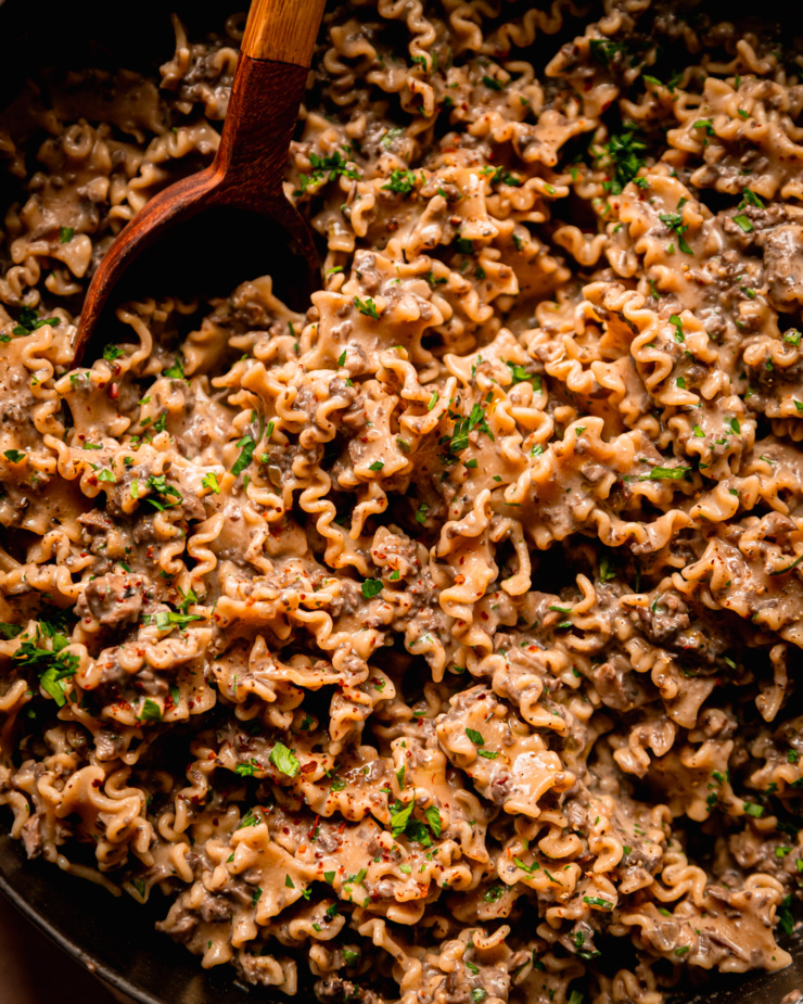 An up close, overhead shot shows some creamy vegan pasta with a finely chopped mushroom and miso sauce. The pasta shape is like little ruffles.