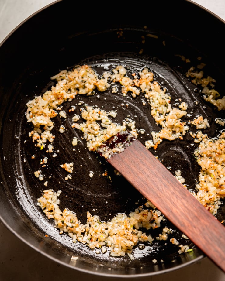 An overhead shot shows sautéed shallots, garlic, and thyme in a pot with a wooden cooking utensil.