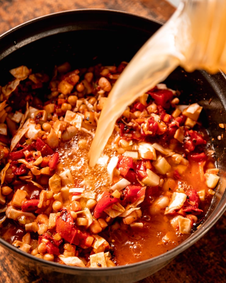 An overhead shot shows vegetable stocking being poured into a pot of diced sautéed vegetables and beans.