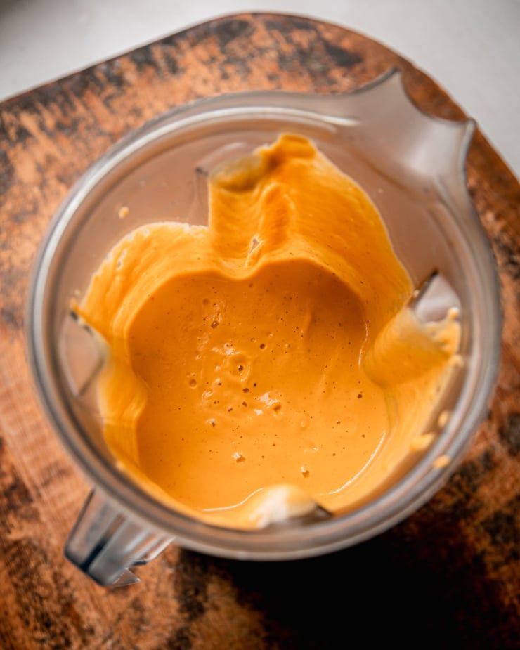 An overhead shot shows a blended up, super creamy vegan truffle sauce in a blender pitcher.